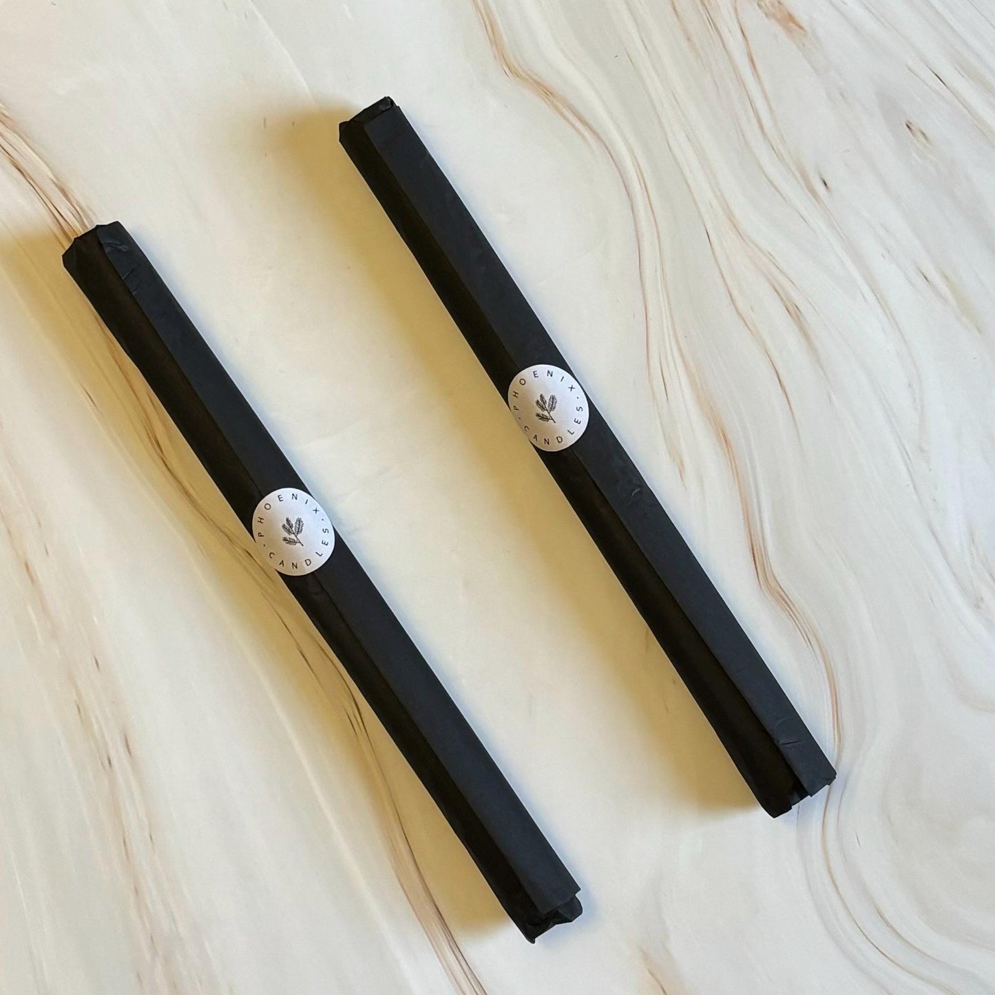 Two black rectangular objects with white circular labels are placed on a marble surface.