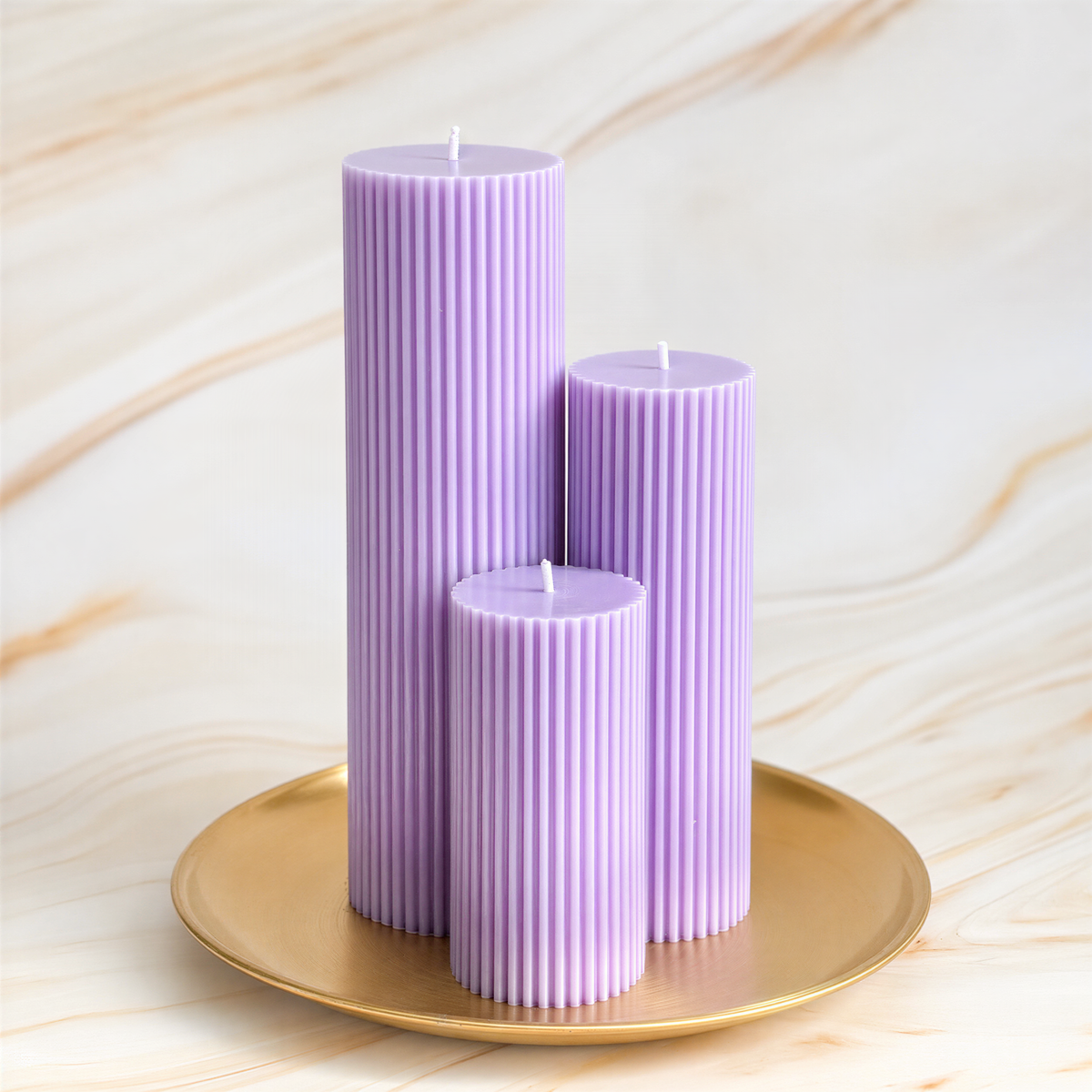 Three tall, cylindrical purple candles are displayed on a gold plate against a marble background.