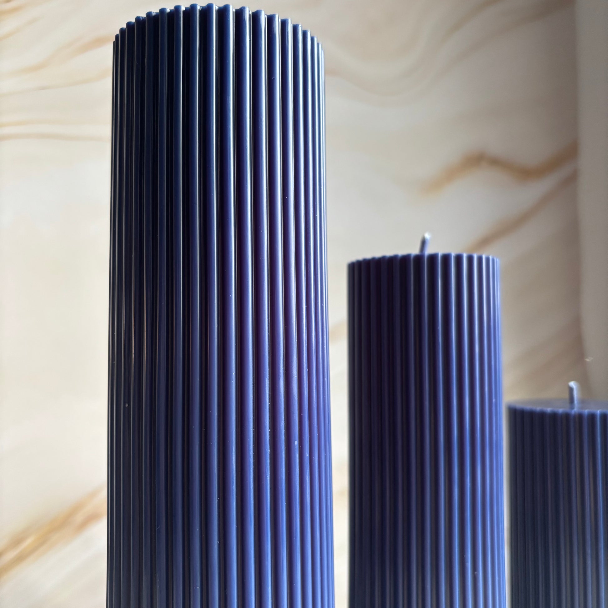 three tall, cylindrical candles with a dark blue color.