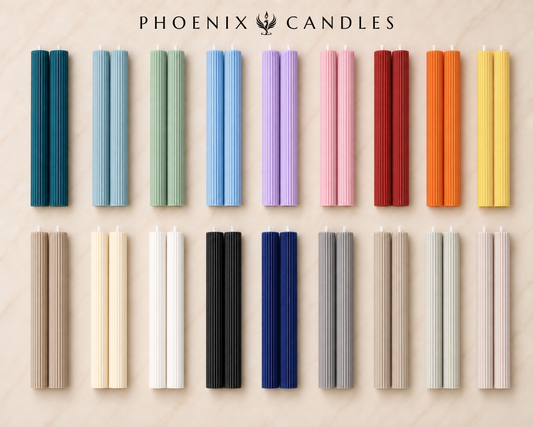 a collection of 16 candles in various colors and shapes, arranged in a grid-like pattern on a light-colored background.